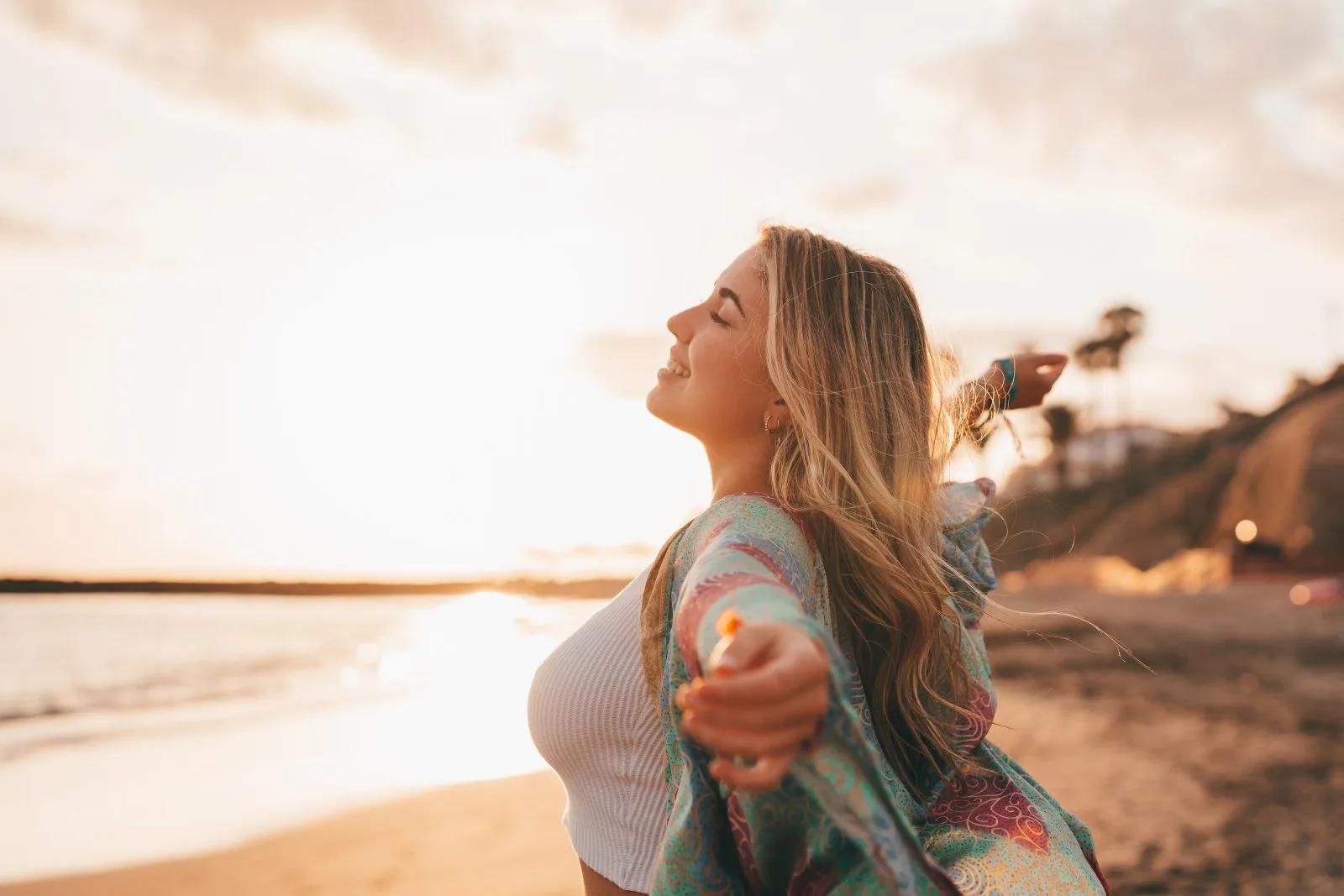 Woman with arms open on the beach at sunset – online psychiatry in San Francisco, CA